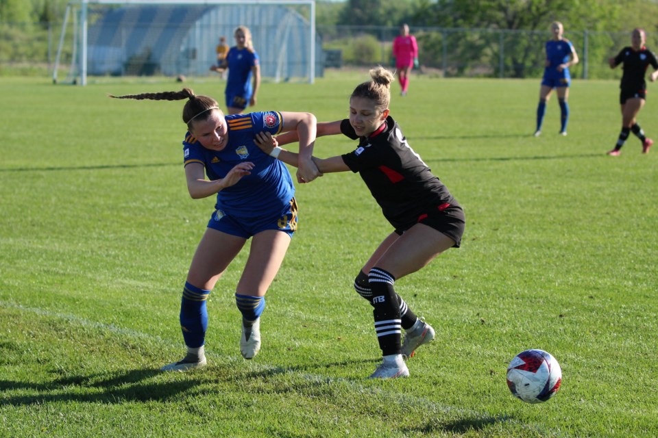 Impact forward Brenna Paquin, in blue, fights through Edmonton BTB's Julia Makoloski during a match on June 4 in Riel Park. JACK FARRELL/St. Albert Gazette