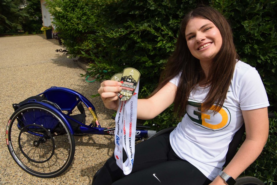 GOLDEN GIRL — Sturgeon County athlete Maggie Slessor shows off the gold medals she won in the 100 and 200 m races at the 2023 Bell Canadian National Track and Field Championship held July 27-30 in Langley, B.C. Behind her is the chair she used at the event. KEVIN MA/St. Albert Gazette