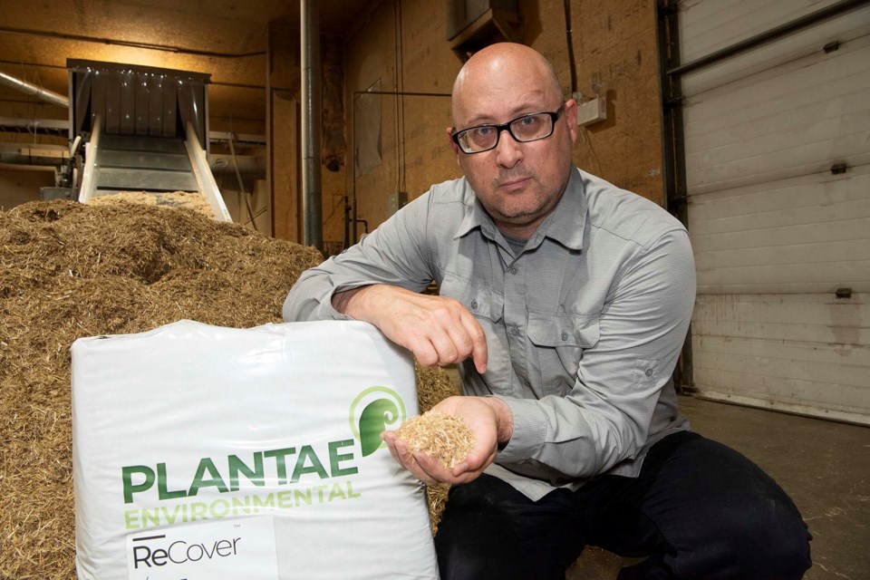 FANCY FLUFF — Plantae Environmental president Treveor Kloeck holds a sample of his company’s ReCover hydraulic erosion control mulch, which uses processed straw instead of plastic mats to prevent erosion. Behind him is some unprocessed straw and the processing machinery. KEVIN MA/St. Albert Gazette