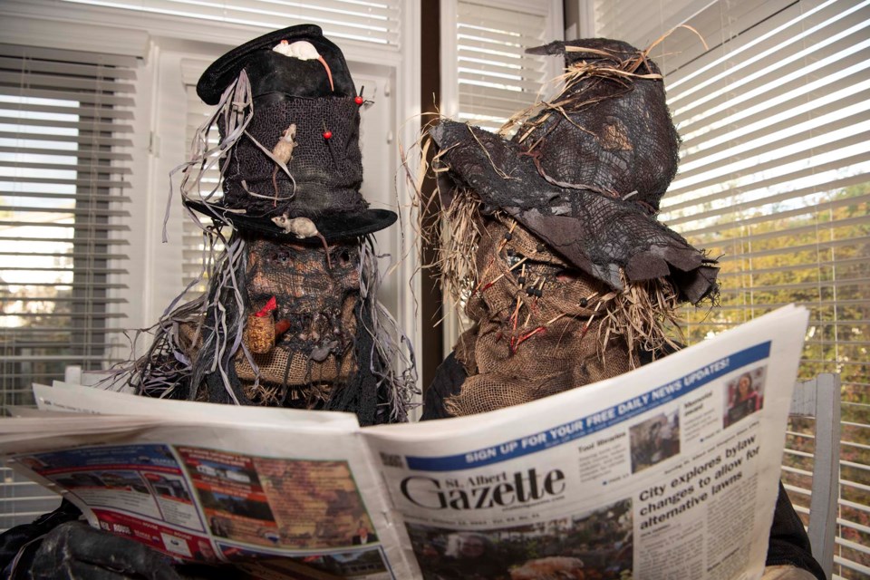 MONSTROUS NEWS — Ingrid (left) and Brian Carli, AKA Mrs. and Mr. Halloween, demonstrate how their homemade costumes look while reading a copy of the Gazette. The duo will be sporting all-new outfits this Oct. 31. KEVIN MA/St. Albert Gazette