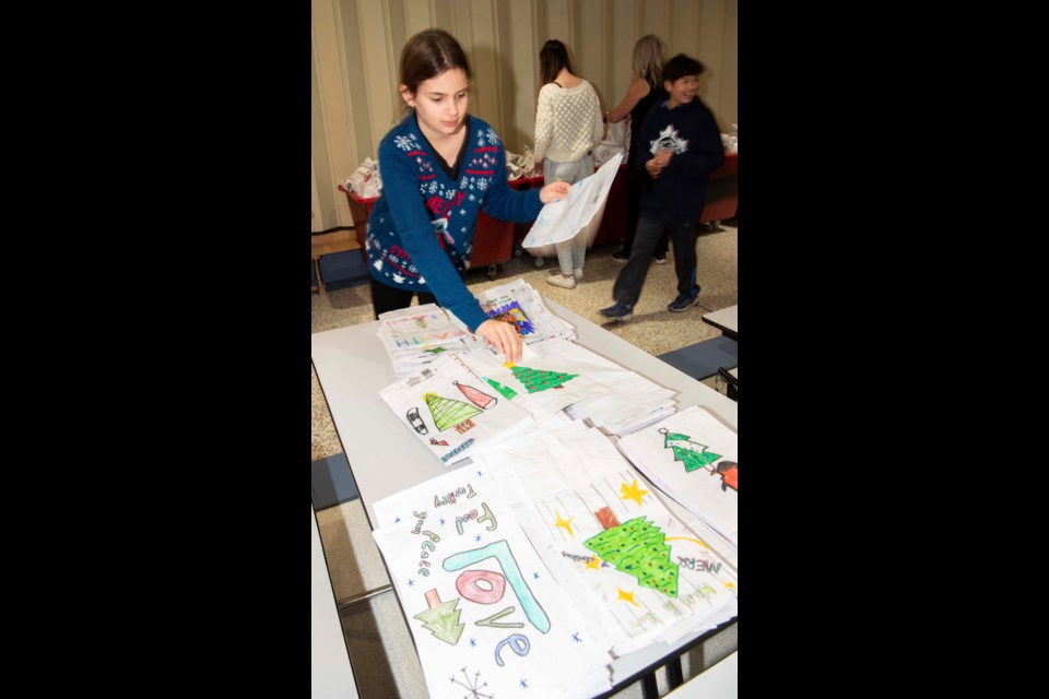 MADE WITH CARE — ESSMY Grade 7 student Alexie Chauvet selects gift bags to fill with presents for Edmonton Remand Centre inmates on Dec. 14, 2023. The bags were decorated by St. Albert elementary students. KEVIN MA/St. Albert Gazette