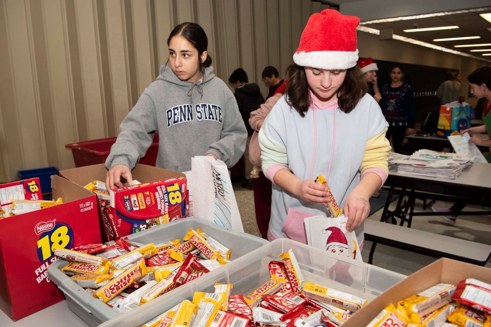 SWEET TREATS — ESSMY student Callie Busque (right) packs candy for gift bags for inmates at the Edmonton Remand Centre on Dec. 14, 2023. Each bag contained three chocolate bars. KEVIN MA/St. Albert Gazette