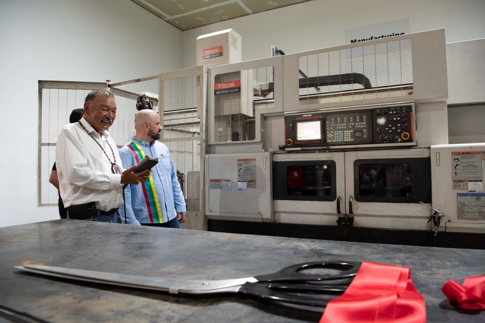 FIRE IT UP — Alexander Chief George Arcand Jr., in white, smiles as he fires up the Mazak Multiplex 6200 automatic milling machine during the grand opening of the Alexander Valve and Supply plant in Alexander Aug. 19, 2022. Run by Ken Braget, in blue, the plant is the first such facility built on a Canadian First Nation reserve. In the foreground are the scissors used in the plant's ribbon cutting ceremony moments earlier. KEVIN MA/St. Albert Gazette