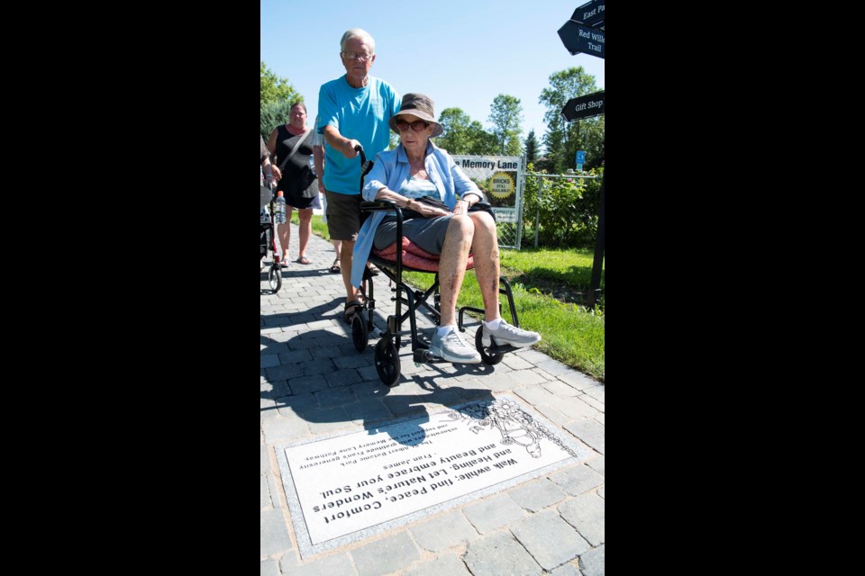 FIRST GUEST — St. Albert resident Lee Dioszeghy, assisted by Iain Forest, was the first person to roll down Memory Lane when it opened at the St. Albert Botanic Park Aug. 18, 2022. Dioszeghy said she used to live next to the park and has walked its paths for decades. KEVIN MA/St. Albert Gazette