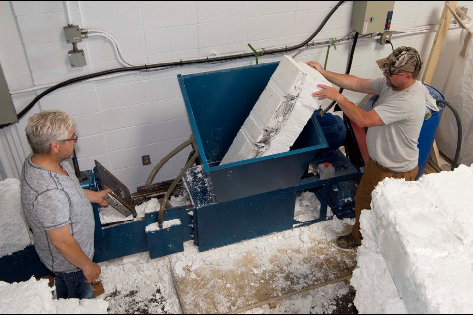 GRIND AND CRUSH — Styro Re Cycle cofounders Don Fink, left, and Leighton Larson run a chunk of Styrofoam through their compactor. The machine uses a grinder and an auger to compress Styrofoam to 1/40th of its original size to create dense bricks like the one in the lower right. KEVIN MA/St. Albert Gazette