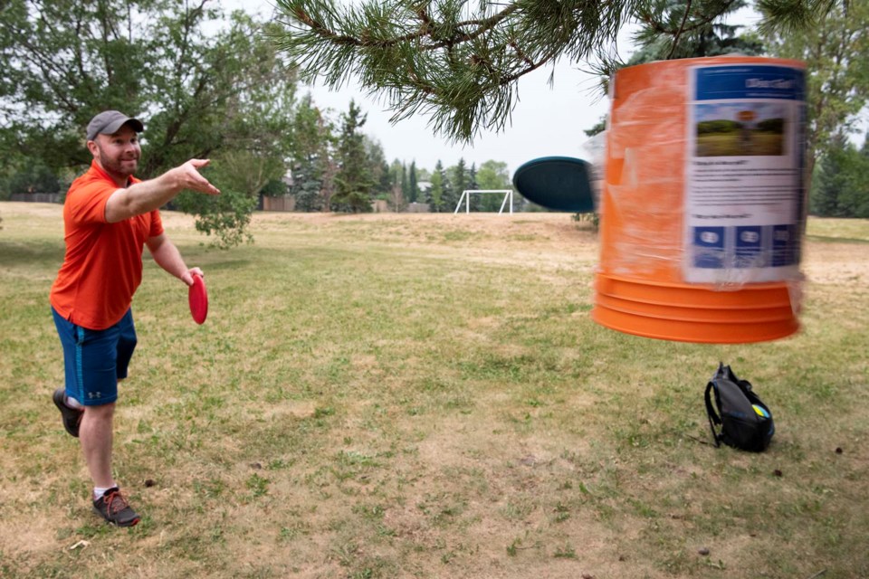 ON TARGET — St. Albert disc golf player Nick Legault demonstrates how to make a short putt at the temporary Langholm Park disc golf course on July 15, 2021. Legault created the course in 2019, which has proven popular during the pandemic. KEVIN MA/St. Albert Gazette