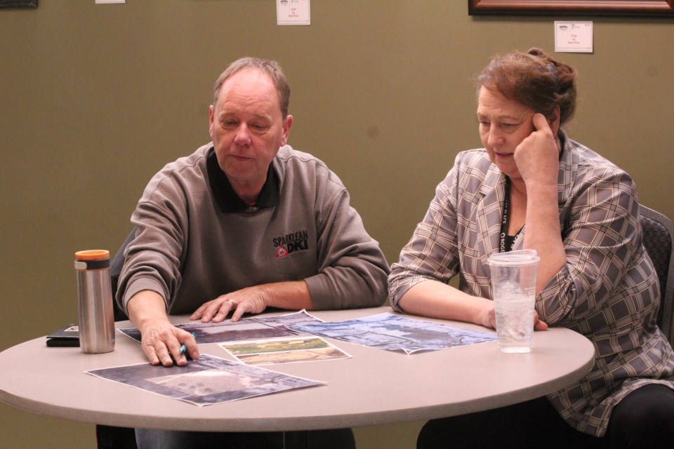 Seniors Association treasurer, Mike Howes, left, and the Association's executive director Linda Ensley, right, compare Millennium Park renderings to drone-captured photos of Red Willow Place and Lions Park. JACK FARRELL/St. Albert Gazette