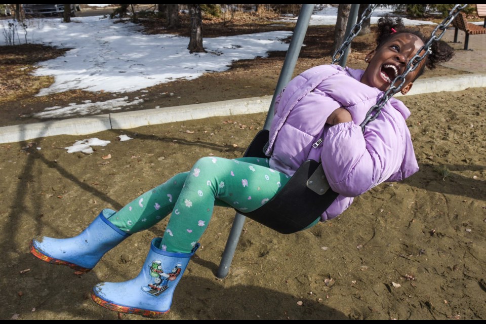 Five-year-old Heavenly Kulu had fun on the swings with a push from her sister Fina, 16, at Lions Park in St. Albert on Saturday Mar 25, 2023.(JOHN LUCAS/St Albert Gazette)
