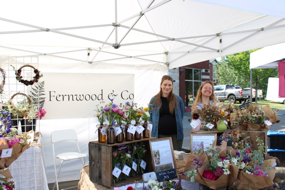 Abby Kozma (left) and Payton Simmons (right) standing at their booth at the St. Albert Farmers' Market. They sell fresh and dried bouquets that are grown by Kozma. 