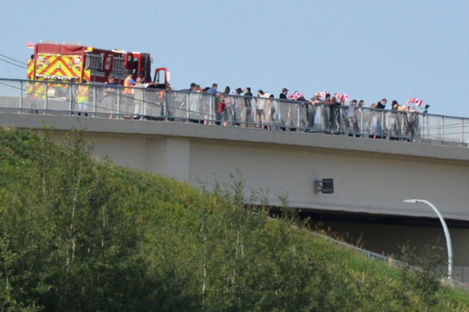 Volunteer extras waved flags on an overpass for a scene for Fallen Heroes: Their Journey Home. SCOTT HAYES/St. Albert Gazette