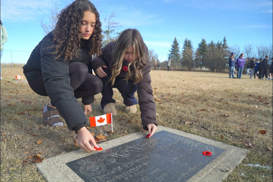 Ruby Driscoll and Kahlan Bowden, both 14, lay poppies on the grave of veteran Capt. D. E. McNiven during the No Stone Left Alone ceremony at the St. Albert Municipal Cemetery Nov. 4, 2024.