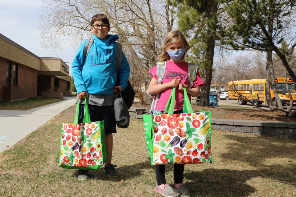 Daniel Grekul, grade 5, and Katie Grekul, grade 1, haul stuff home from Bertha Kennedy in preparation for three weeks of at home learning. May 6, 2021.