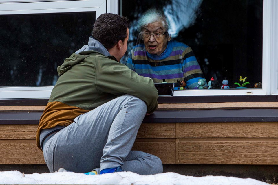 Jordan Dore, of St. Albert, talks with his great-grandmother Theresa Charest, 102, via their smart phones and through the window of Chateau Mission Court on April 14, 2020, while practicing social distancing measures. Former Gazette photographer Chris Cobourne won second place with this photo in the AWNA 2020 photography category.  CHRIS COLBOURNE/St. Albert Gazette