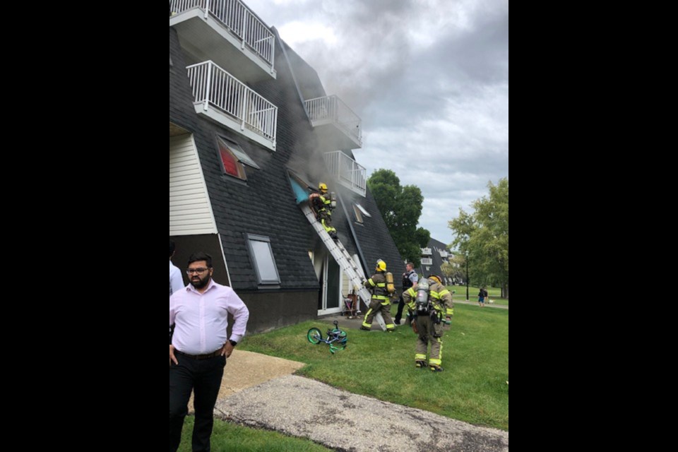 Firefighters carry a woman out of a burning apartment on Rivercrest Crescent Friday afternoon. CAROLYN MARTINDALE/Photo