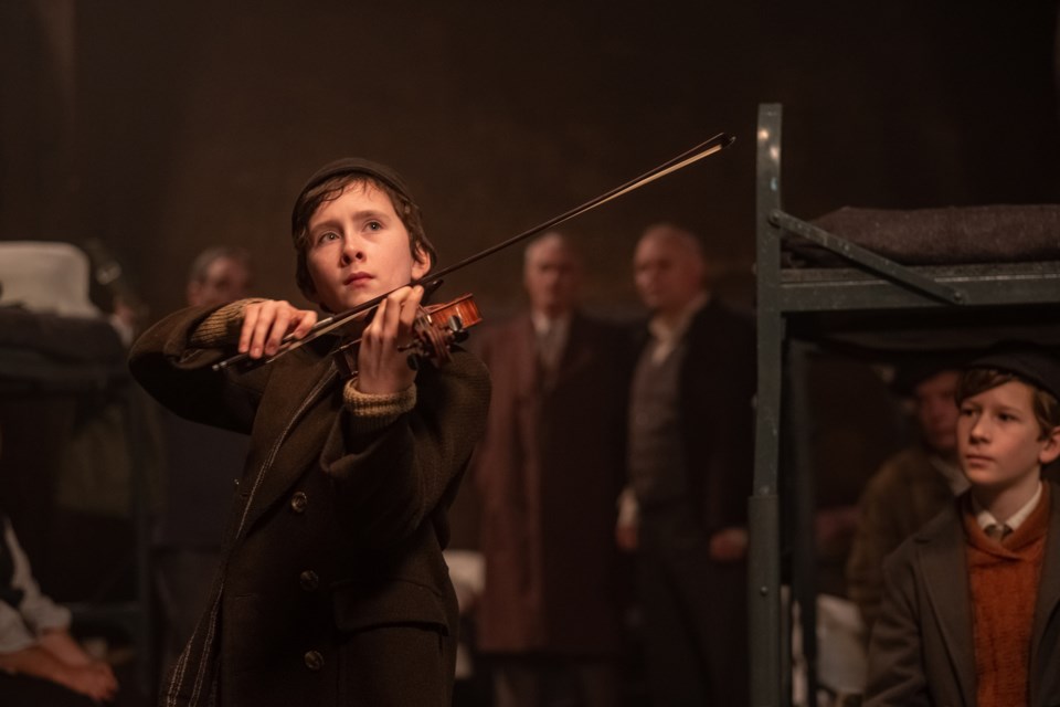 Young Dovidl (played by Luke Doyle) plays the violin in an air raid shelter as WWI rages on in London.  ELEVATION PICTURES/Photo