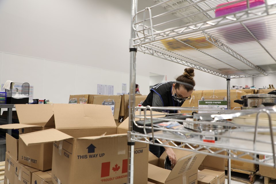 Melissa Swith unpacks boxes on her first day working with the new Goodwill St. Albert store.