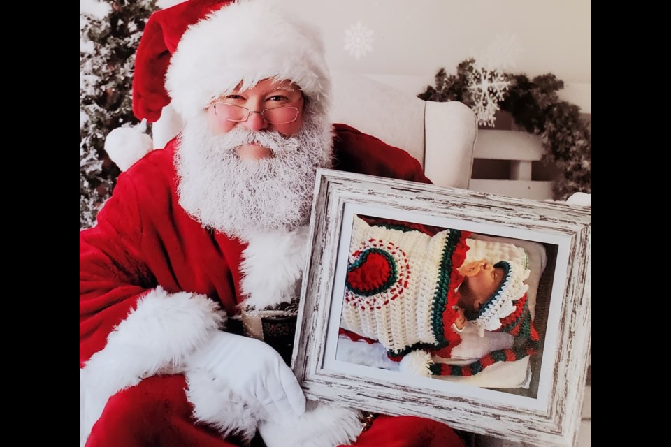 Santa holds a photo of an anonymous Misericordia hospital NICU baby. Photo: Nadine Scherger/Wand & Willow