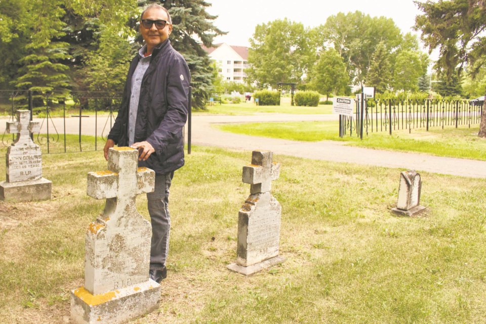 Bruce Gladue stands in the graveyard at the St. Albert Catholic Parish and behind him, just steps away from the area, the Metis local will be searching for the unmarked gravesites of Metis and Indigenous children who attended the St. Albert Youville residential school. JENNIFER HENDERSON/St. Albert Gazette