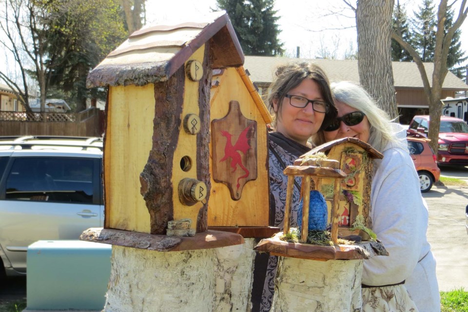 Jennifer (left) and Silva Galea build birdhouses that are both functional and artistic. The photo, taken in Jennifer's front yard, showcases two rustic birdhouses and a blue decorative dinosaur egg. ANNA BOROWIECKI/St. Albert Gazette