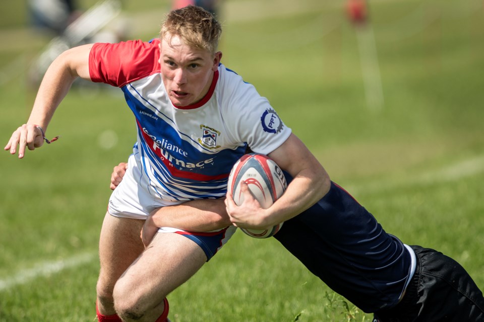 HITCHING A RIDE – Brian Fitzpatrick of the St. Albert Rugby Football Club drags a Clan defender in his path during Saturday's premier men's match at Airways Park. Fitzpatrick's unconverted try late in the first half pulled SARFC to within nine points of the Clan, en route to the come-from-behind 36-26 victory. Fitzpatrick's penalty kick on the second-last play of the match sealed the deal.
DAN RIEDLHUBER/St. Albert Gazette