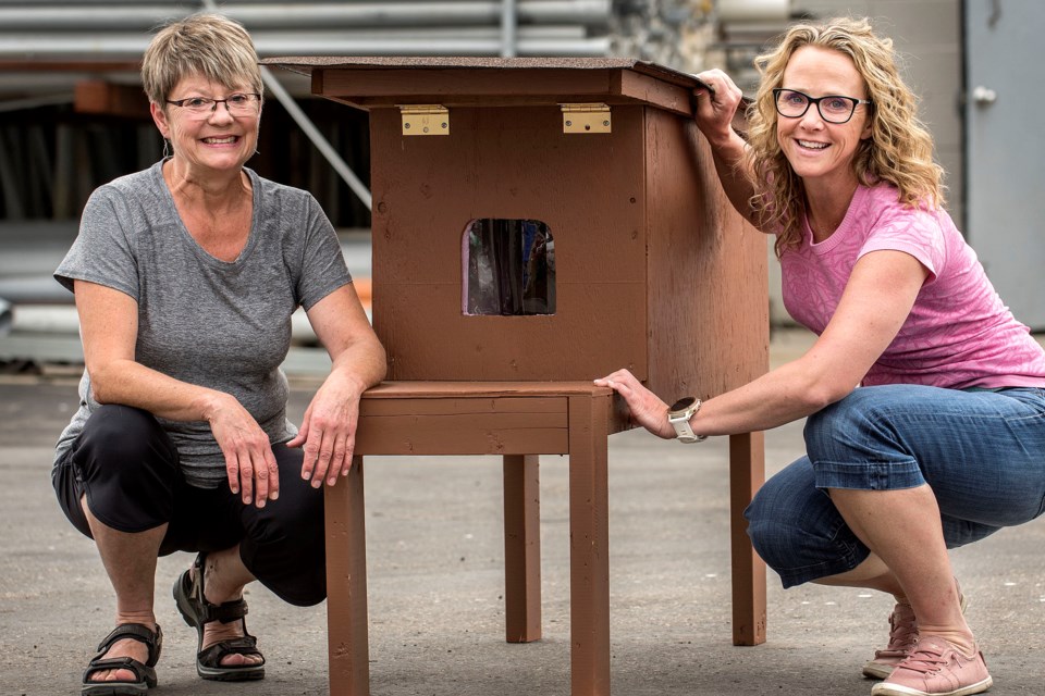 Lori Nagazina, left, shows Tari Kelly the inside of the cat house she built and delivered to Kelly's Riel Park business in St. Albert on Aug. 23, 2019. Feral cats often gather in Riel Park. DAN REIDLHUBER/St. Albert Gazette