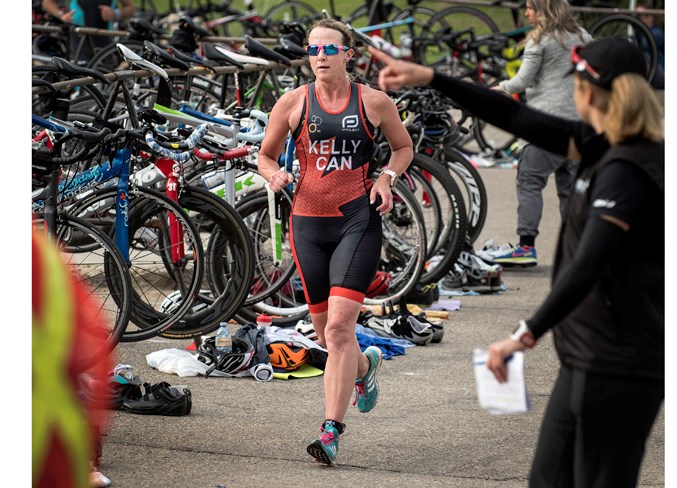 SPEEDSTER – Tari Kelly of Sturgeon County is pointed in the right direction by a course official while running through the bicycle transition area during the 30th annual St. Albert Triathlon at Fountain Park Recreation Centre. Kelly, 49, was the first female finisher in Sunday's sprint race (750-metre swim, 20-kilometre bike, five-km run) in 1:17:25.2 for 22nd place overall.
DAN RIEDLHUBER/St. Albert Gazette