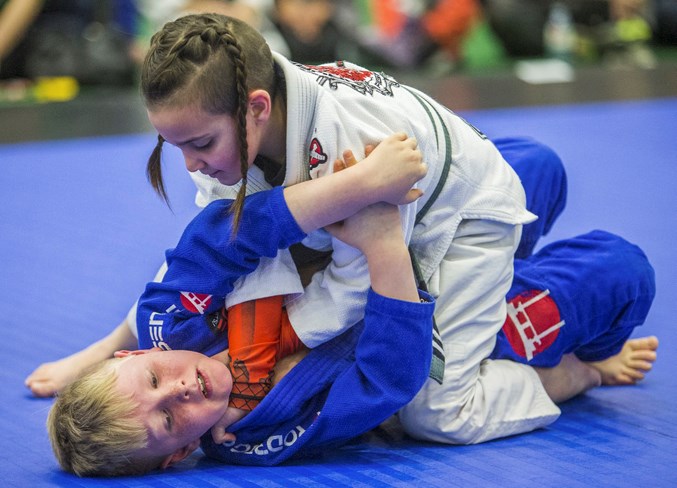 UPPER HAND – Zoe Gable of St. Albert attempts a cross choke on David Pedersen of Spruce Grove in the 7-8 years old white and grey belt division match at the True North Grappling championships Saturday at Servus Credit Union Place. The Brazilian jiu-jitsu tournament featured 120 youths among the 319 competitors.
CHRIS COLBOURNE/St. Albert Gazette