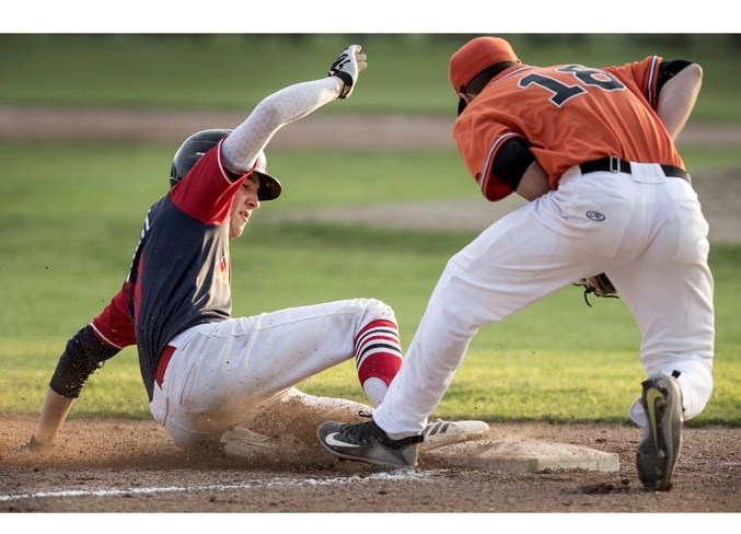 SLIDER – Kade Knight of the 18U AAA St. Albert Cardinals arrives safely at third as Nate Sellinger of the senior AAA St. Albert Tigers fields the throw in the Saturday night feature game at the Tigers Baseball Association tournament at Legion Memorial Park. The Tigers pulled off the 7-5 extra-inning victory in pool A of the nine-team competition.
DAN RIEDLHUBER/St. Albert Gazette