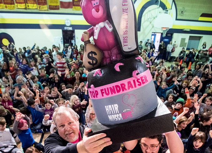 Leo Nickerson Elementary School teachers and organizers of the Hair Massacure program, Chris Akins, left, and Sydney Taylor, on March 1 hoist a top fundraising trophy the school has won for several years running. The school hopes to win the trophy again this year.
DAN RIEDLHUBER/St. Albert Gazette