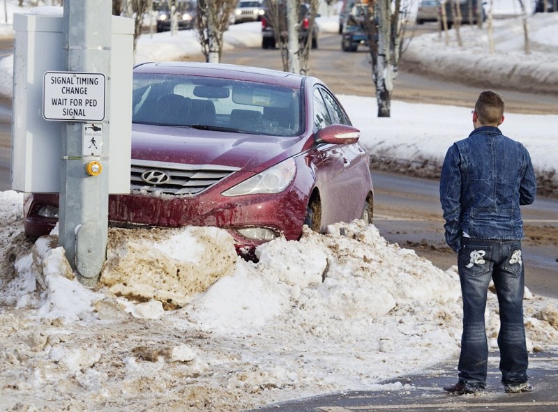 A driver surveys the scene after his car ended up in a snow bank