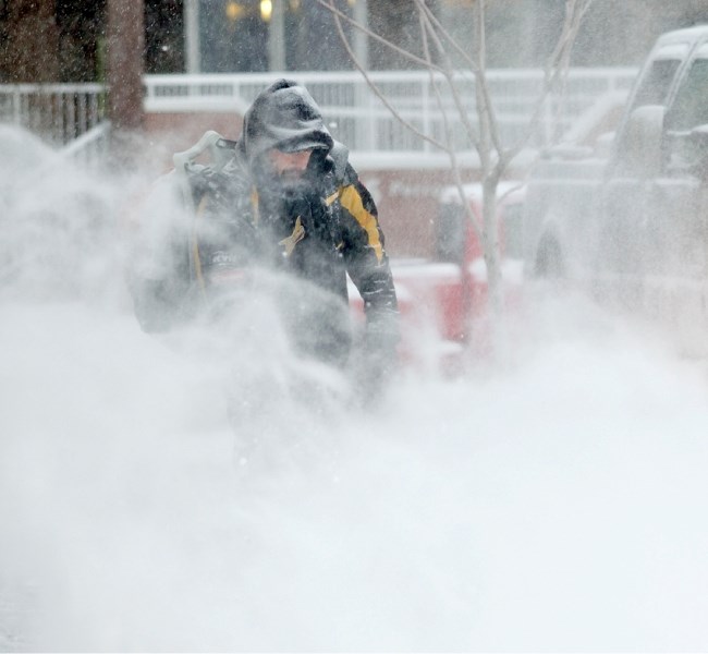 Darren Jodouin uses a snow blower to clear the sidewalks around The Rock business salon on Friday afternoon along St. Thomas Street.