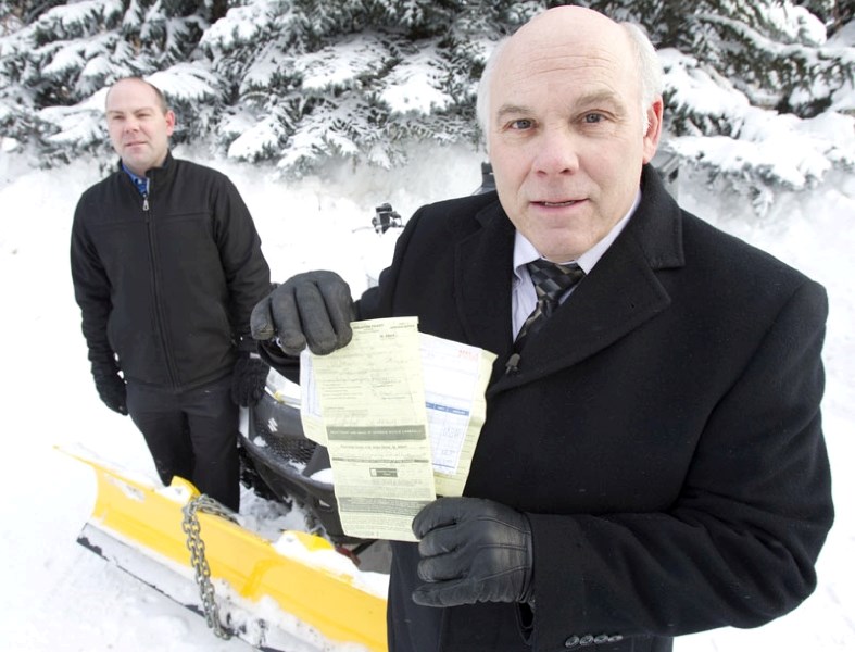 Dr. Jon Cooper holds up the $250 ticket he received after using an ATV to clear snow from sidewalks near his property on Bellerose Drive