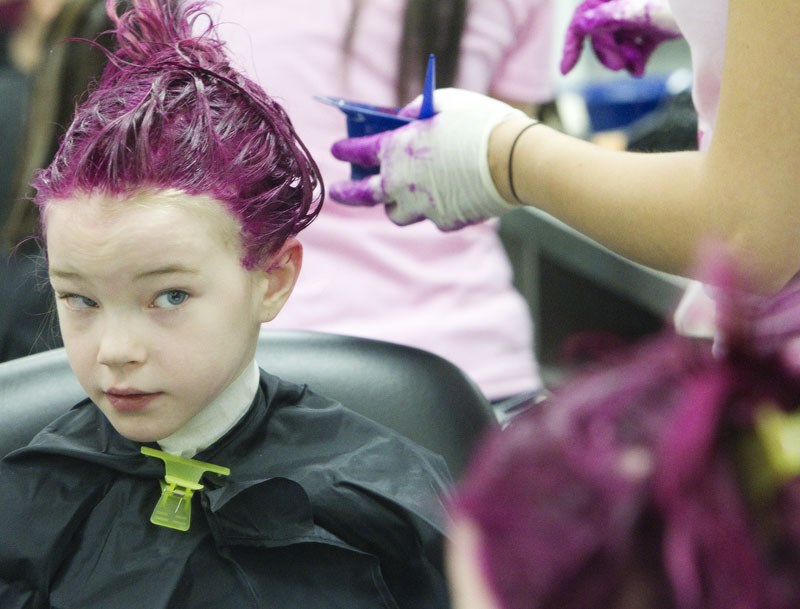 Madysen Steele checks out her new pink hair Thursday as she participated in the Go Pink charity event at Paul Kane High School. Students in the cosmetology program gave