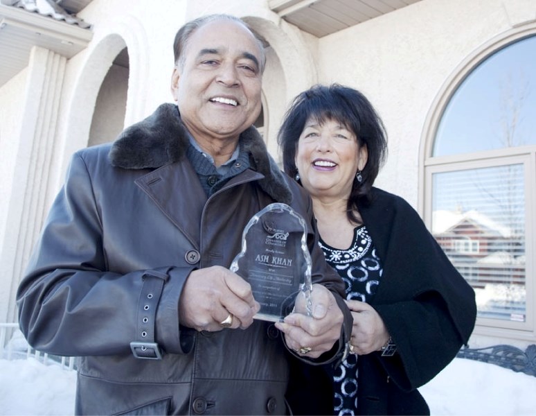 Ash Khan displays the honorary lifetime membership award he received from the chamber of commerce while standing next to his wife Sharon at their Erin Ridge home. Khan was