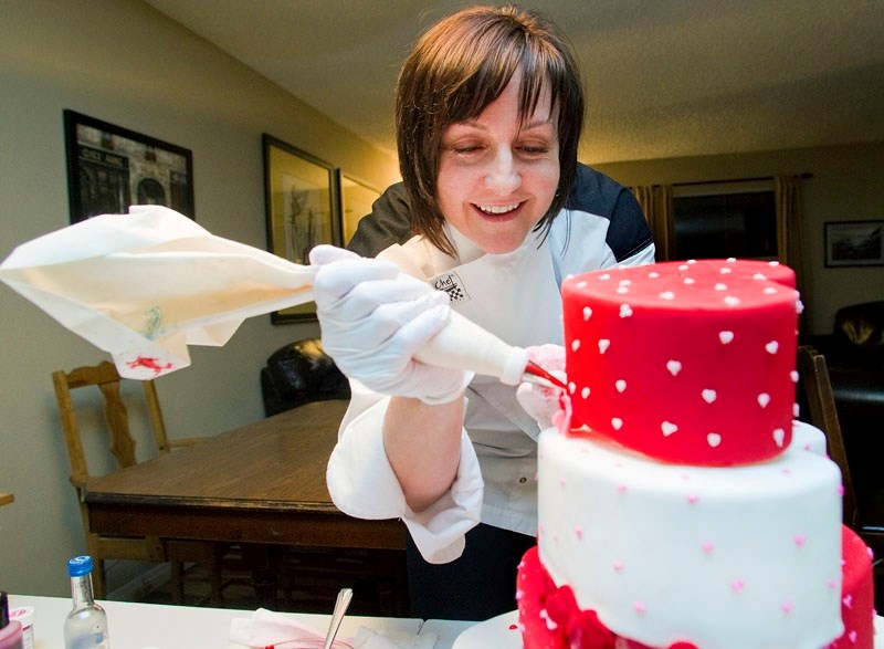 Michelle Andrade of Bogato Custom Cake Designs works on a cake in her home. Andrade was bitten by the decorative cake bug after watching some shows on the Food Network.
