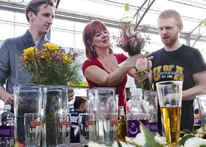 Karen Wilson of Hole&#8217;s Greenhouses &amp;amp; Gardens provides a few floral arranging pointers to Matthew Gresiuk (left) and Nick Dehod (right) during the inaugural Beers