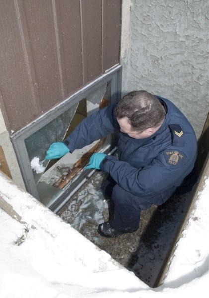 Cpl. Daryn Henderson of K Division&#8217;s forensic identification section dusts a broken basement window for prints Thursday morning at St. Albert&#8217;s Christian Reformed 