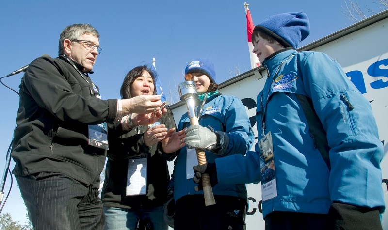 (L-R) Mayor Nolan Crouse relights a torch for the relay to mark the opening of the 2011 Alberta 55 Plus Winter Games with chair Sandra Fenton and torchbearers Payton McNeil