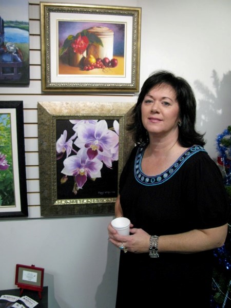 St. Albert resident Cheryl Wilkes poses beside one of her orchid paintings. Wilkes was one of three St. Albert artists to be recognized for her art during February&#8217;s