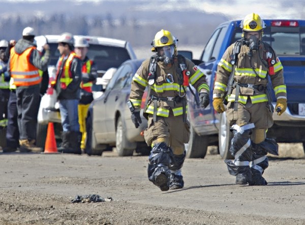 St. Albert firefighters walk near the intersection of Giroux Rd. and Ray Gibbon Drive on Wednesday as emergency crews responded to a gas leak in a nearby field. Traffic was