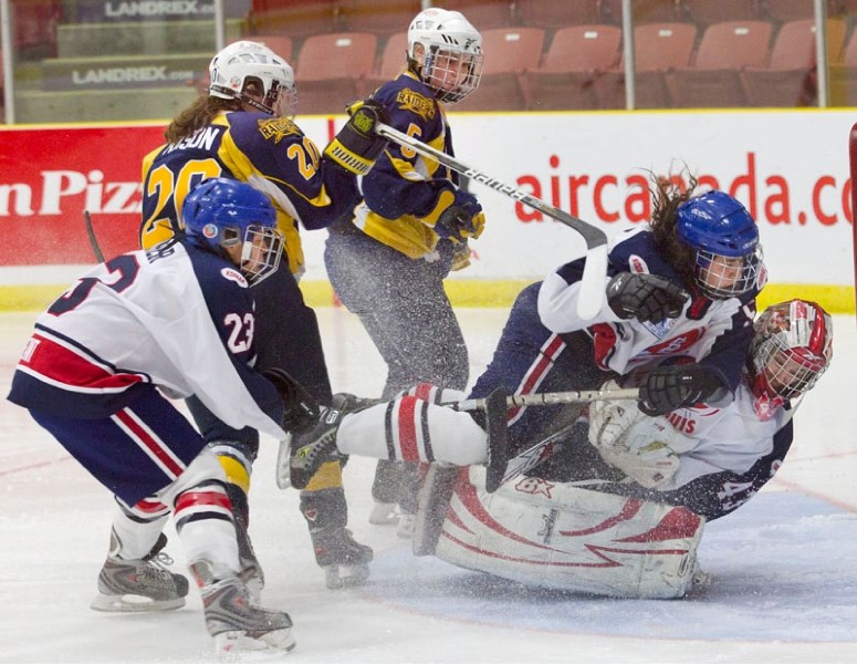 Quebec goaltender Laurie Anne Beaulieu is bowled over by a teammate after stopping Angela Mason (20) of the St. Albert Slash during the last round-robin game at the Esso Cup