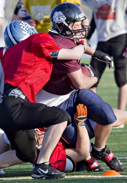 St. Albert Storm running back Robert Blunden is wrapped up by a pair of tacklers during Tuesday&#8217;s practice at the Riel Park turf field. Today at 4 p.m. the Storm