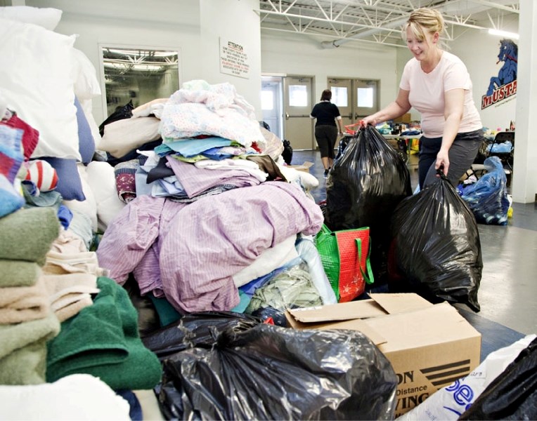 Wendy Skjersven of Morinville adds donated clothing to the large pile of donated goods at the Ray McDonald Sports Centre on Monday evening. The arena became a drop-off centre 