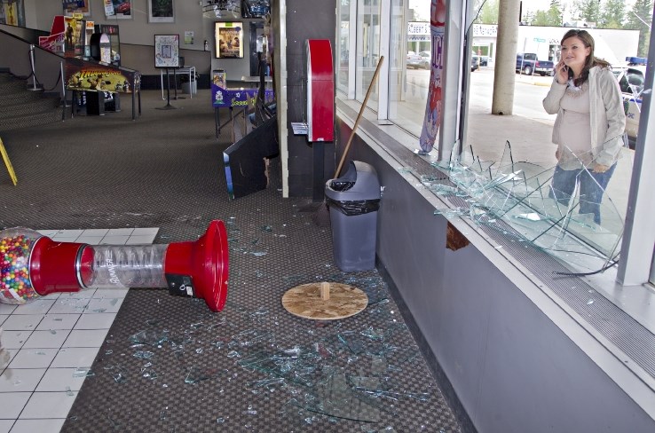 Grandin Theatre general manager Katy Van Bruggen uses a cellphone to talk to an employee through a shattered window of the movie house. A small deer crashed through the glass 