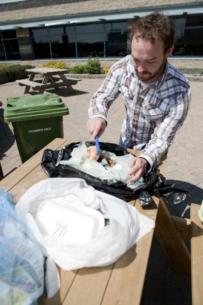 City of St. Albert solid waste program co-ordinator Christian Benson picks through a typical bag of St. Albert trash. He&#8217;s currently examining a bag of buns