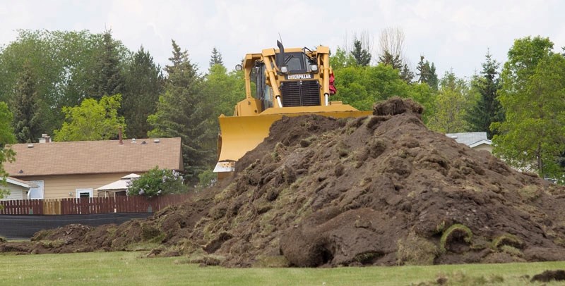 A bulldozer moves a mound of dirt at the site of Aurora Place