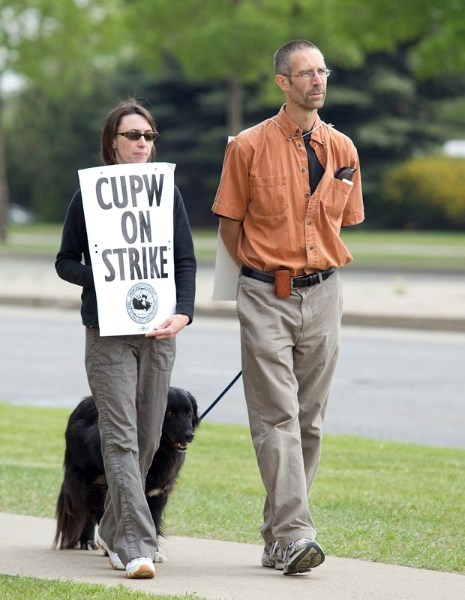 (L-R) Postal workers Deborah Richmond and Jeff Hillas walk the picket line along Hebert Road Wednesday afternoon. The workers were taking shifts picketing as rotating job