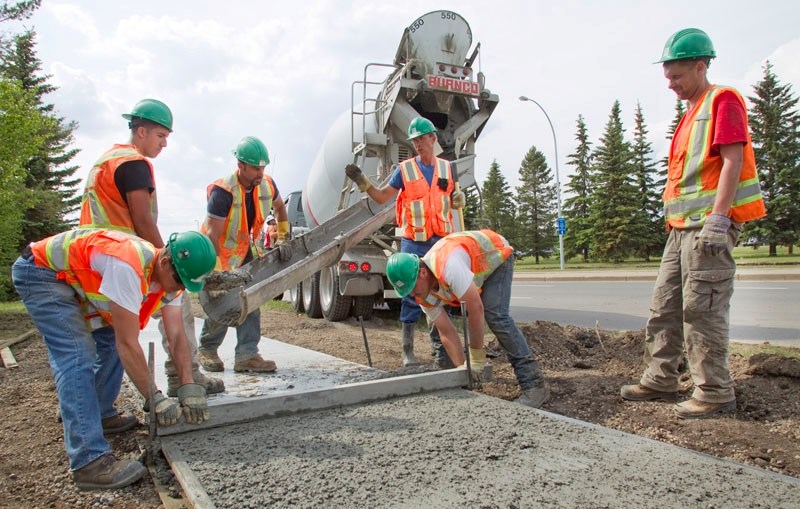 Workers with North West Paving install sidewalks along Boudreau Road Monday. The work is part of the Anthony Henday Drive connector road improvements.