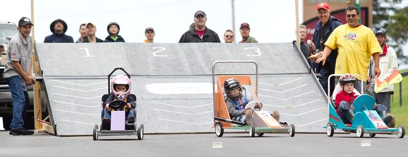 Youngsters from the six- to seven-year-old age group drive down the starting ramp during the Soap Box Derby on Sunday. Families built and painted their purchased soap box