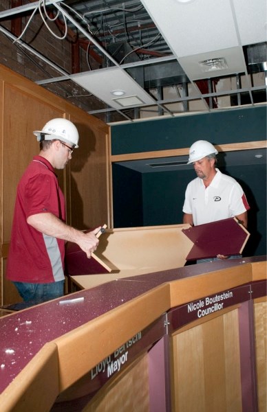 Tyler Reimer (left) and Rick Moser of Synergy Projects haul away portions of the Morinville town council desk as renovations begin at St. Germain Plaza. Crews will spend the